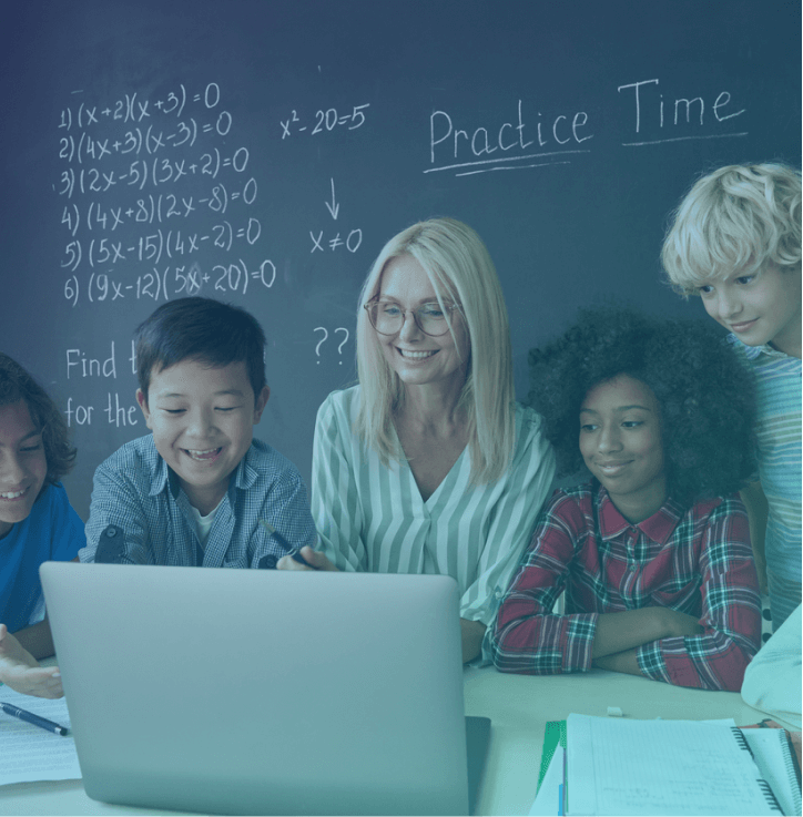 Teacher with students looking at a laptop in the classroom