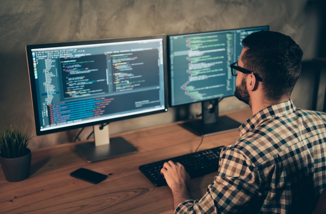 A software engineer sitting behind a desktop and coding