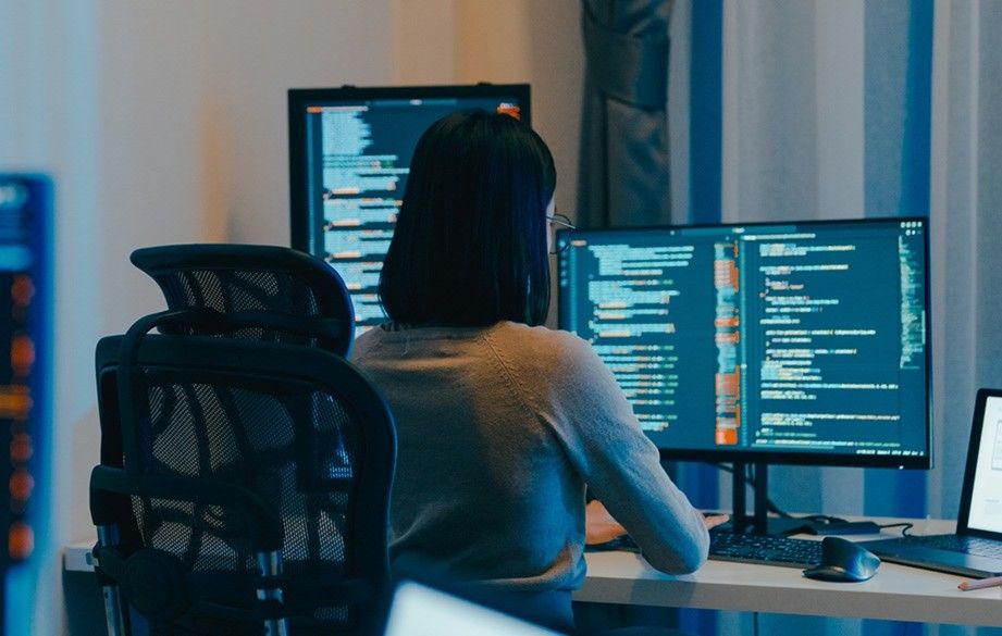 Female programmer sitting at work in front of computer screens